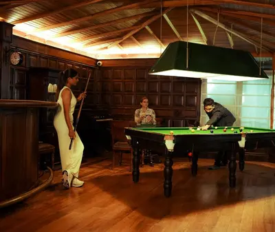 a woman standing in a room with a pool table at Milntown Bungalow 200 years old Colonial Stay in Coonoor in Coonoor