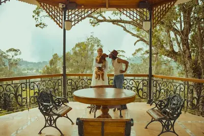 a family standing on a porch with a table at Milntown Bungalow 200 years old Colonial Stay in Coonoor in Coonoor