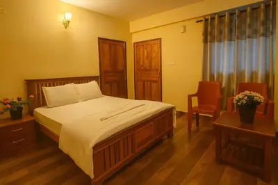 a bedroom with a bed and a table and a chair at Dreamview Cottage by BEN Groups in Ooty