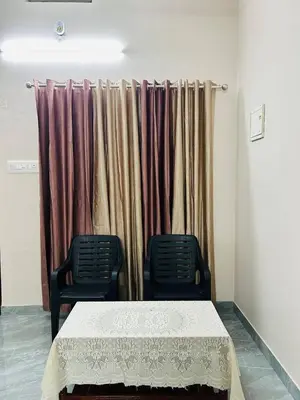 a table and two chairs in front of a curtain at Cosy Stays, 2 Adjacent Apartments in Irinjalakuda in Irinjālakuda