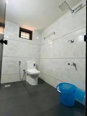 a white bathroom with a toilet and a window at Cosy Stays, 2 Adjacent Apartments in Irinjalakuda in Irinjālakuda