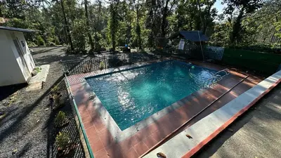 a large swimming pool with a fence around it at Hima Pool Villa in Padinjarathara