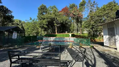 a park with a bench and a fountain at Hima Pool Villa in Padinjarathara