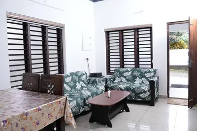 a living room with two couches and a table at Serene Cottage - Home away from Home in Vythiri