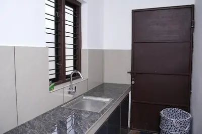a kitchen with a sink and a black refrigerator at Serene Cottage - Home away from Home in Vythiri