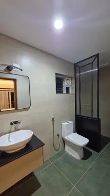 a bathroom with a sink and a toilet and a mirror at SUKOON Stays - Nestled among the misty hills and lush forests in Vythiri
