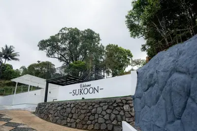 a building with a sign on a rock wall at SUKOON Stays - Nestled among the misty hills and lush forests in Vythiri