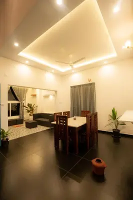 a living room with a table and chairs and a couch at SUKOON Stays - Nestled among the misty hills and lush forests in Vythiri