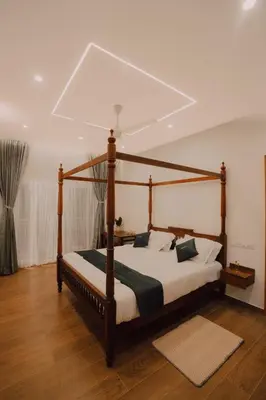 a bedroom with a wooden canopy bed with white sheets at SUKOON Stays - Nestled among the misty hills and lush forests in Vythiri