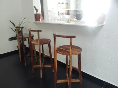 a kitchen with three wooden stools at a counter at SUKOON Stays - Nestled among the misty hills and lush forests in Vythiri