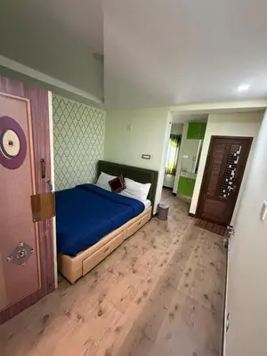a bedroom with a blue bed and a wooden floor at Forever Cottage by sait's hospitality in Ooty