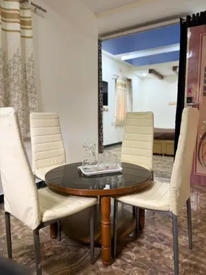 a dining room table with white chairs and a mirror at Forever Cottage by sait's hospitality in Ooty