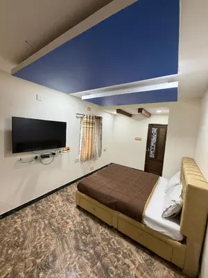 a bedroom with a bed and a flat screen tv at Forever Cottage by sait's hospitality in Ooty