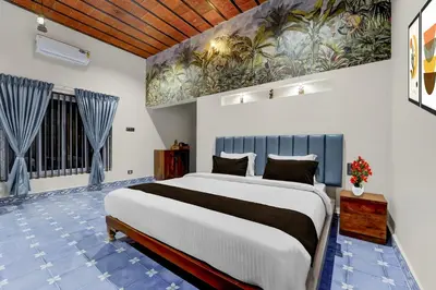 a bedroom with a large bed and a painting on the wall at Palette Mithalai Farm by CheckIn | Garden | Pvt Pool | Coimbatore in Coimbatore