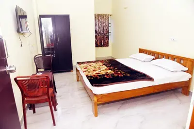 a bedroom with a bed and two chairs in it at SOWMYA RESIDENCy in Piriyāpatna