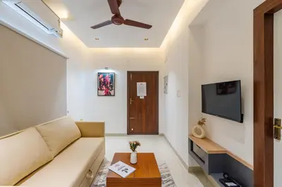 a living room with a couch and a flat screen tv at Everest Serenity Service Apartment in Pīlamedu