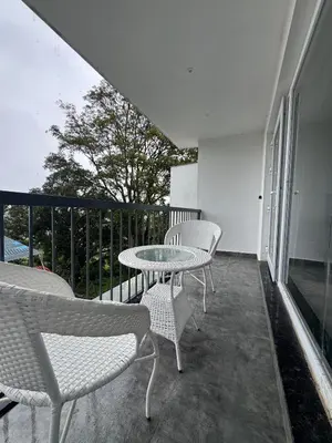 a balcony with a table and chairs on a balcony at Black Dot Stays - Mehand Veera Residency in Kodaikānāl