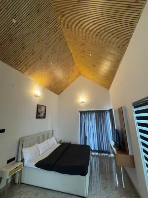 a bedroom with a bed in a room with a wooden ceiling at Black Dot Stays - Mehand Veera Residency in Kodaikānāl
