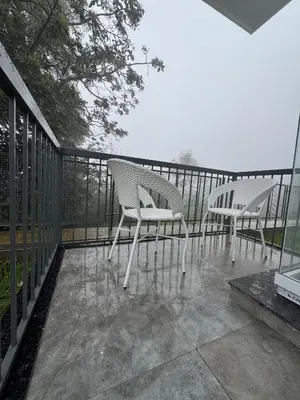 two chairs sitting on a balcony with a fence at Black Dot Stays - Mehand Veera Residency in Kodaikānāl
