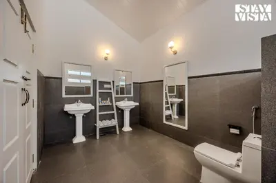 a bathroom with two sinks and two mirrors at StayVista at Mudra Tattva - Pvt Pool,Lawn,Jacuzzi 2BR Luxury Rooms in Suntikoppa