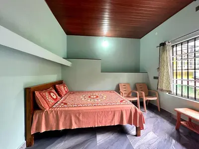 a bedroom with a bed and two chairs and a window at Leaf links Coorg in Siddapur