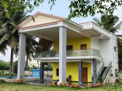 a yellow and white house with a balcony at Blue Moon Homestay in Mysore