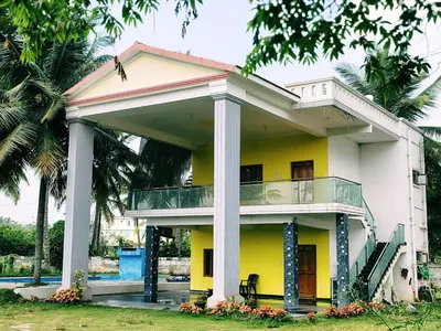 a yellow and white house with a balcony at Blue Moon Homestay in Mysore