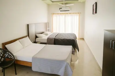 a hotel room with two beds and a chair at Blue Moon Homestay in Mysore