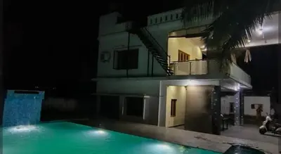 a swimming pool in front of a building at night at Blue Moon Homestay in Mysore