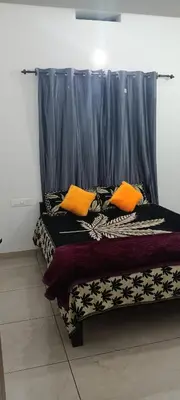 a bed with two orange pillows in a room at Green palace service villa in Kalpetta