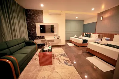 a hotel room with a couch and a bed and a tv at LUMARISE Premium Wayanad Business Hotel in Sultan Bathery