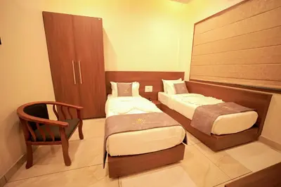 a hotel room with two beds and a chair at LUMARISE Premium Wayanad Business Hotel in Sultan Bathery