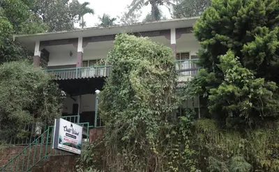 a house with a balcony and a sign in front of it at Chillwind Service villa in Padinjarathara