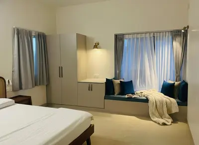 a bedroom with a bed with blue pillows and a window at Nesara Home Stay Mysuru in Mysore