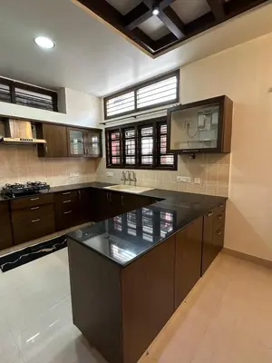 a large kitchen with a large black counter top at Villa Vinaya- Comfort, Calm & Charm in Mysore in Mysore