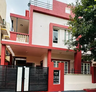 a red and white house with a black fence at Villa Vinaya- Comfort, Calm & Charm in Mysore in Mysore