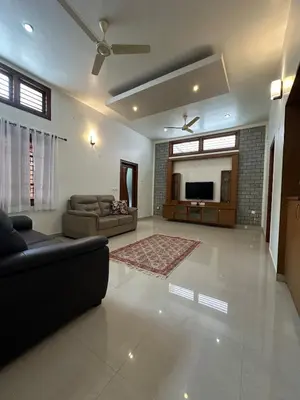 a living room with a couch and a tv at Villa Vinaya- Comfort, Calm & Charm in Mysore in Mysore