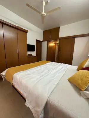 a bedroom with a large white bed with wooden cabinets at Villa Vinaya- Comfort, Calm & Charm in Mysore in Mysore