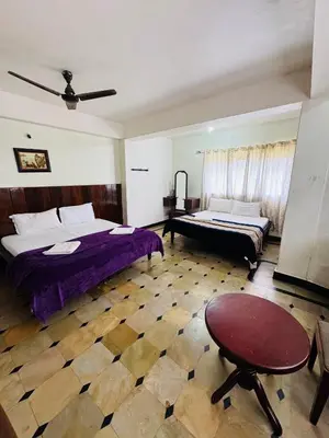 a bedroom with two beds and a table at Hotel caveri comfort in Madikeri