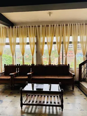 a living room with a couch and a large window at Hotel caveri comfort in Madikeri