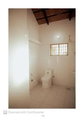 a white bathroom with a toilet and a window at Coorg River Song Homestay in Kushālnagar