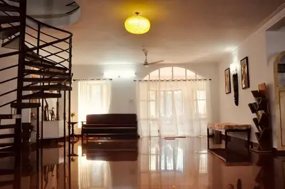 a living room with a couch and a spiral staircase at Coorg River Song Homestay in Kushālnagar