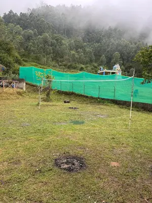 a green fence in a field next to a forest at Kanthalloor puregolds in Kanthalloor