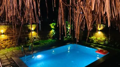 a jacuzzi tub in a backyard at night at Earthen Pool Villa! Redefining Luxury! in Marayoor