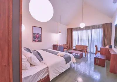 a bedroom with a large bed and a living room at Achutham Cottages Wayanad by VOYE HOMES in Padinjarathara