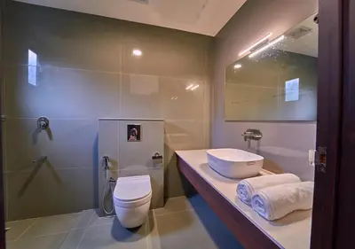 a bathroom with a sink and a toilet and a shower at Achutham Cottages Wayanad by VOYE HOMES in Padinjarathara