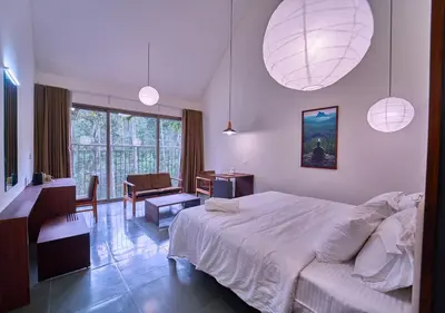 a bedroom with a large white bed and a desk at Achutham Cottages Wayanad by VOYE HOMES in Padinjarathara