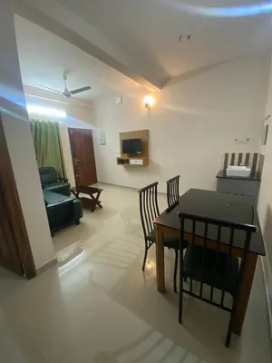 a living room with a table and chairs and a couch at Neurogreen Apartments in Kottakkal