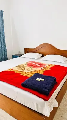 a bed with a red and blue blanket on it at The Haze Land in Ooty
