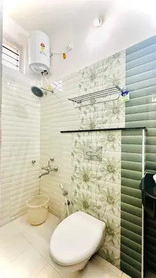 a bathroom with a toilet and a shower with flowers on the wall at The Haze Land in Ooty